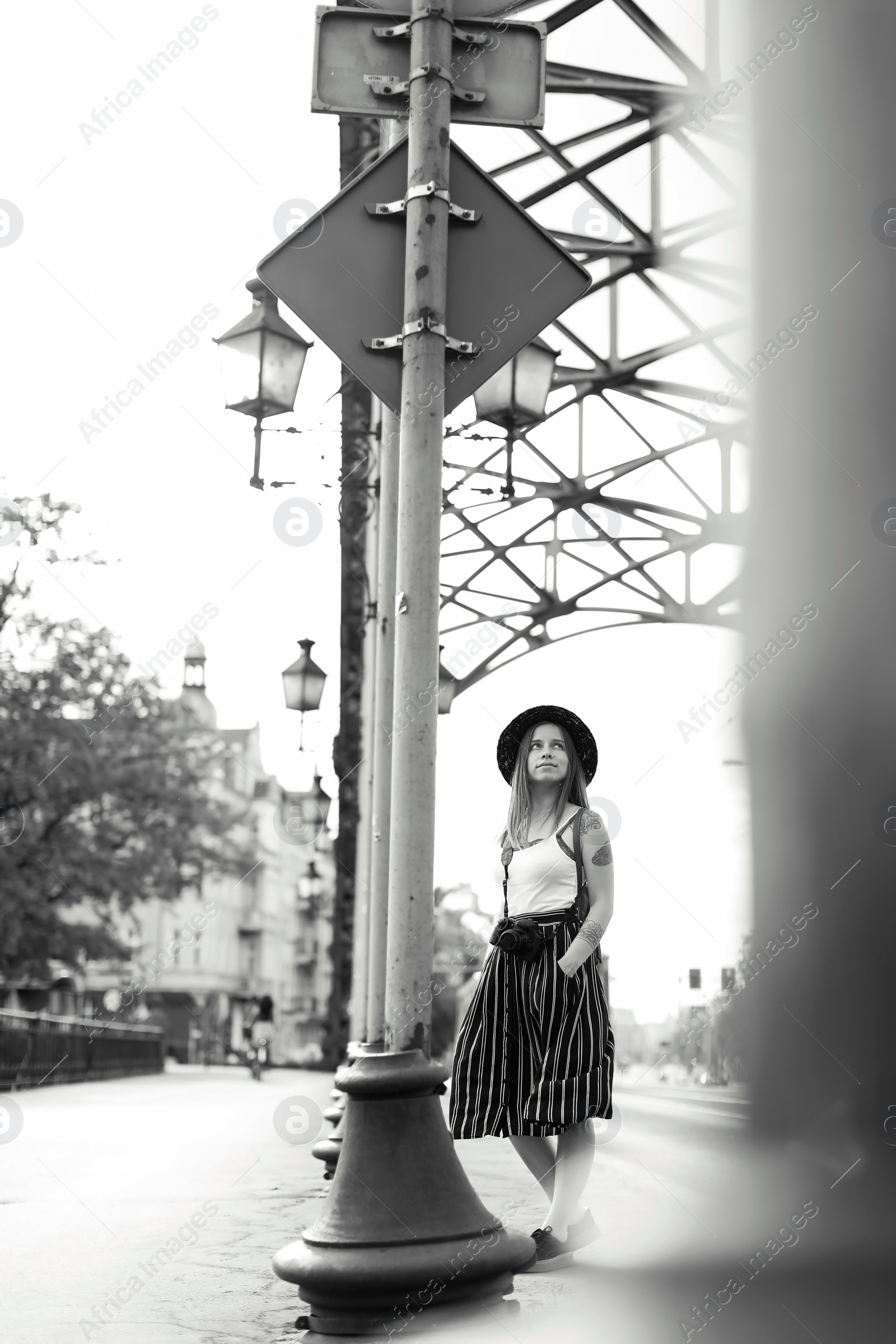 Photo of Young woman with camera on city street, black and white effect