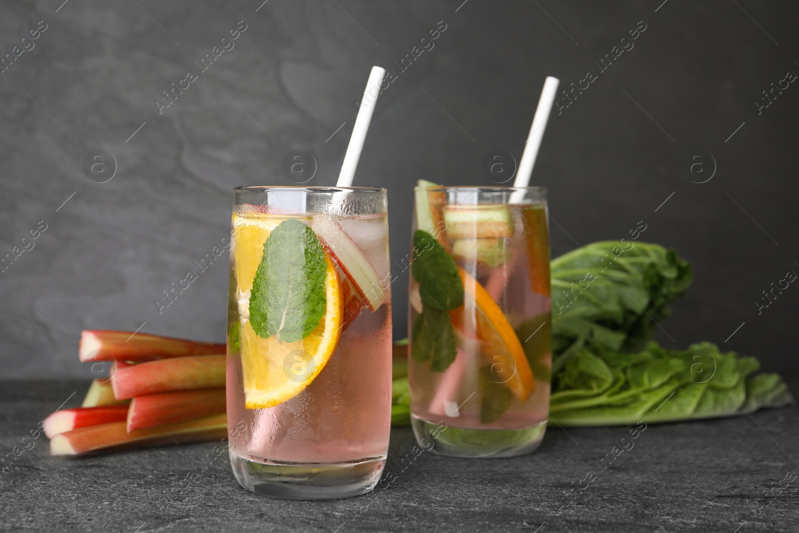 Photo of Tasty rhubarb cocktail with lemon on grey table