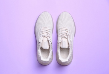 Photo of Stylish sporty sneakers on light violet background, top view