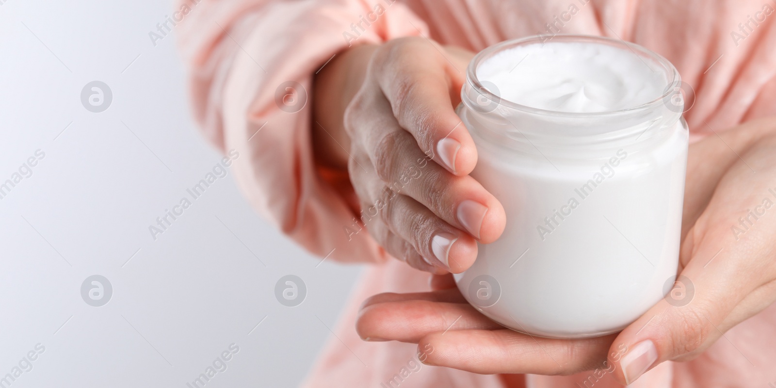 Image of Woman holding jar of hand cream on white background, closeup view with space for text. Banner design