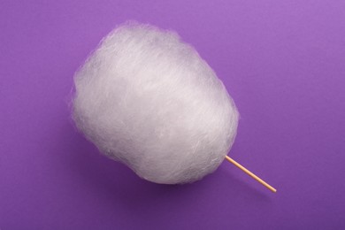 Photo of One sweet cotton candy on purple background, top view