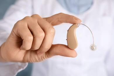 Photo of Doctor holding hearing aid, closeup. Medical device