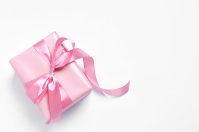 Beautiful gift box with pink bow on white background, top view. Space for text