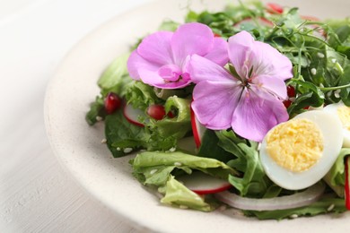 Photo of Fresh spring salad with flowers on white wooden table, closeup