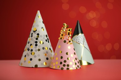 Photo of Beautiful party hats and serpentine streamers on red background