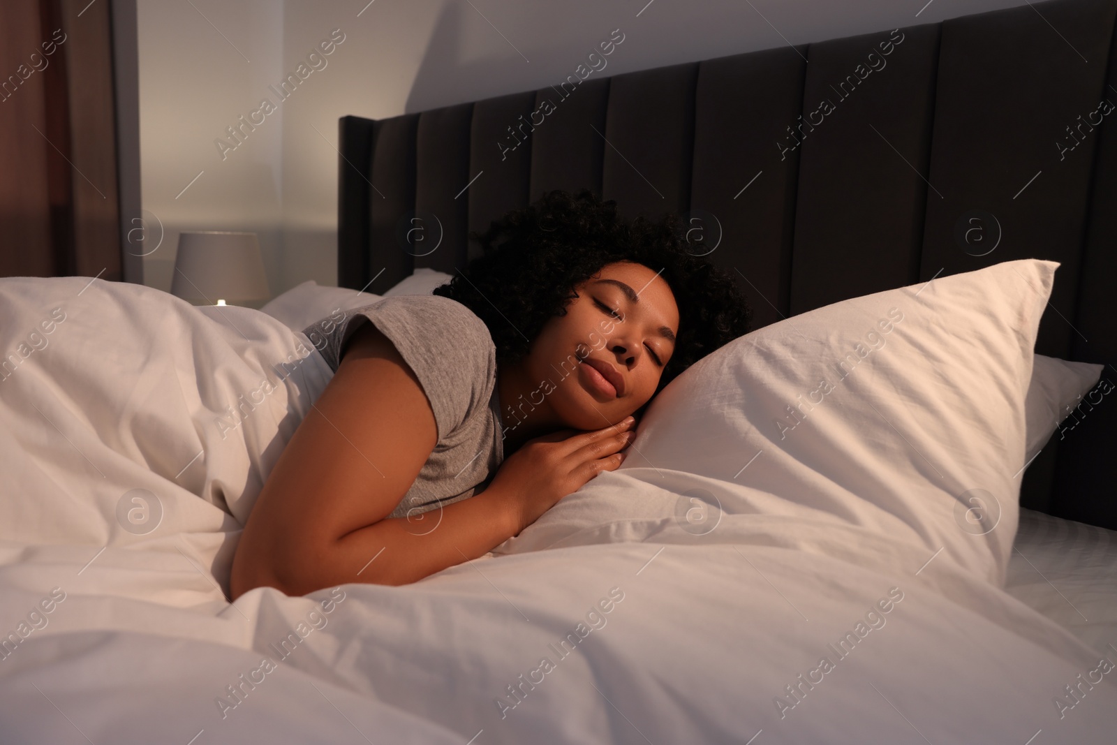 Photo of Young woman sleeping in soft bed at night