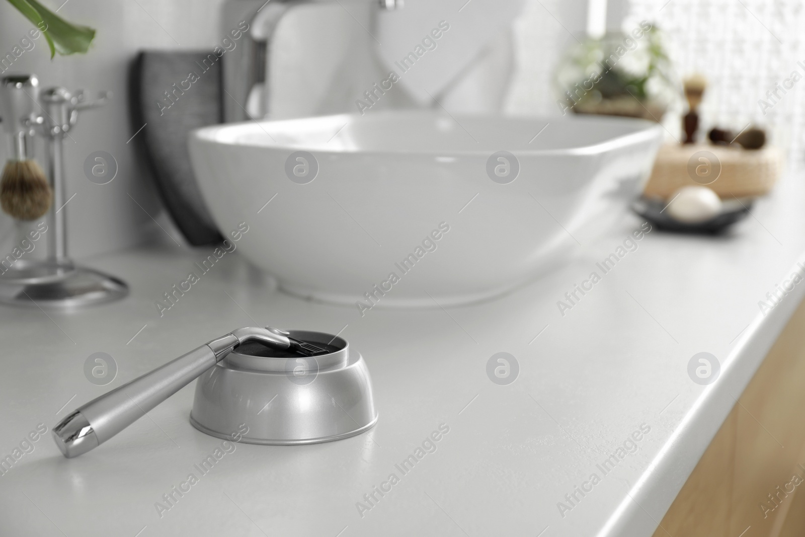 Photo of Modern razor on light countertop in bathroom