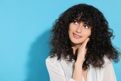 Portrait of beautiful young woman on light blue background, space for text