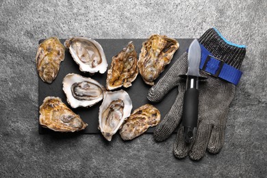 Photo of Fresh oysters and knife on grey table, flat lay