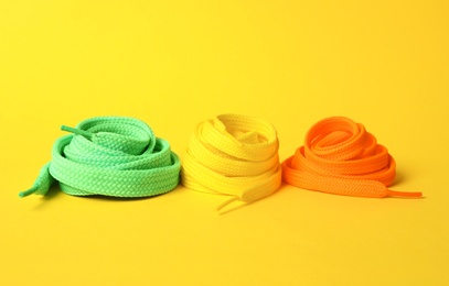 Photo of Different colorful shoe laces on yellow background