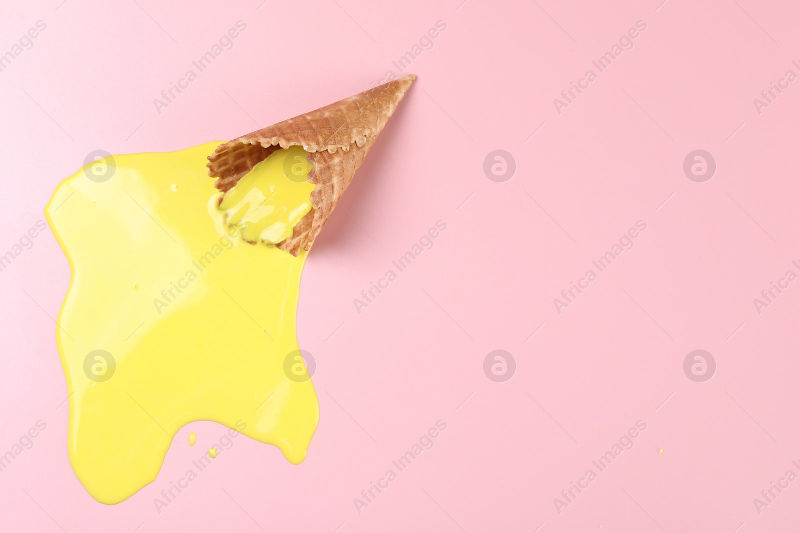 Photo of Melted ice cream and wafer cone on pink background, top view. Space for text