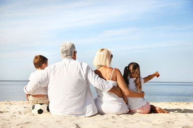 Photo of Cute little children with grandparents spending time together on sea beach, back view