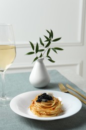 Photo of Tasty spaghetti with tomato sauce and black caviar served on table. Exquisite presentation of pasta dish