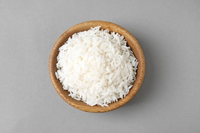 Bowl of tasty cooked rice on grey background, top view