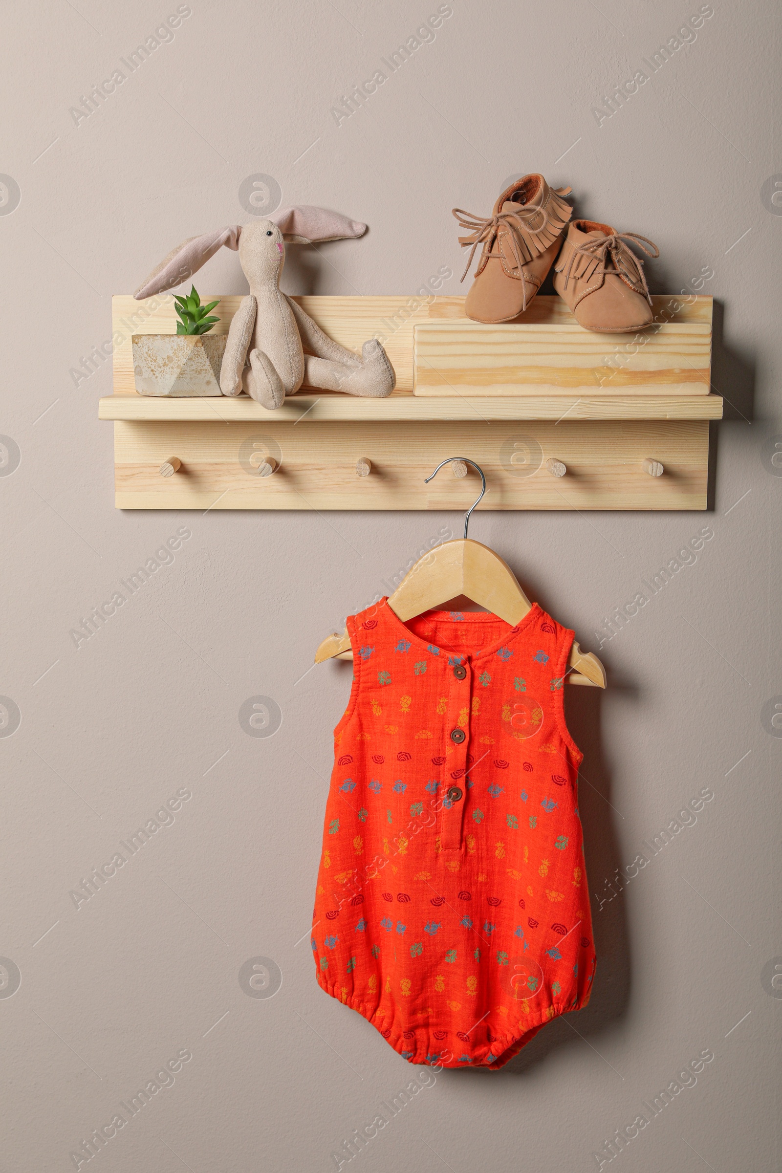 Photo of Baby bodysuit, booties and toy on wooden rack
