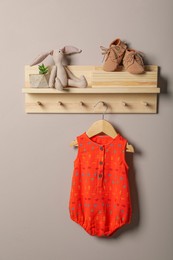 Baby bodysuit, booties and toy on wooden rack