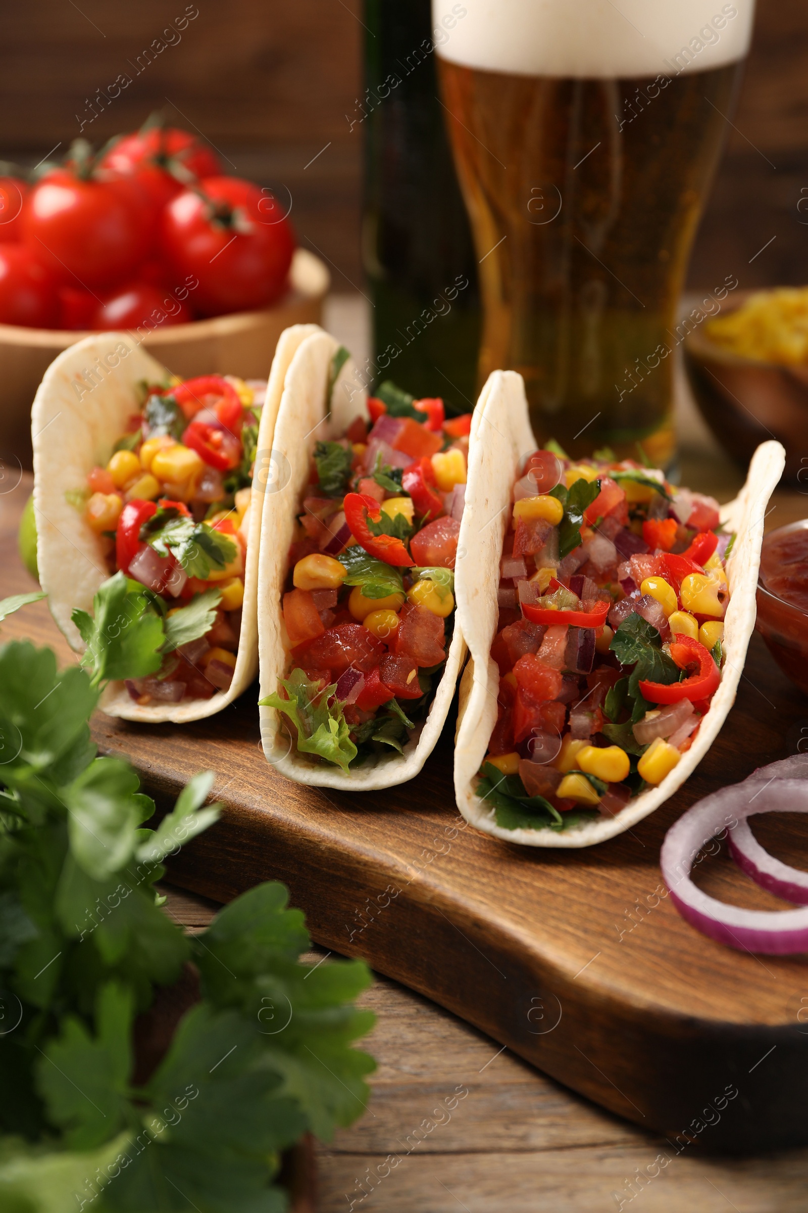 Photo of Tasty tacos with vegetables on wooden table, closeup