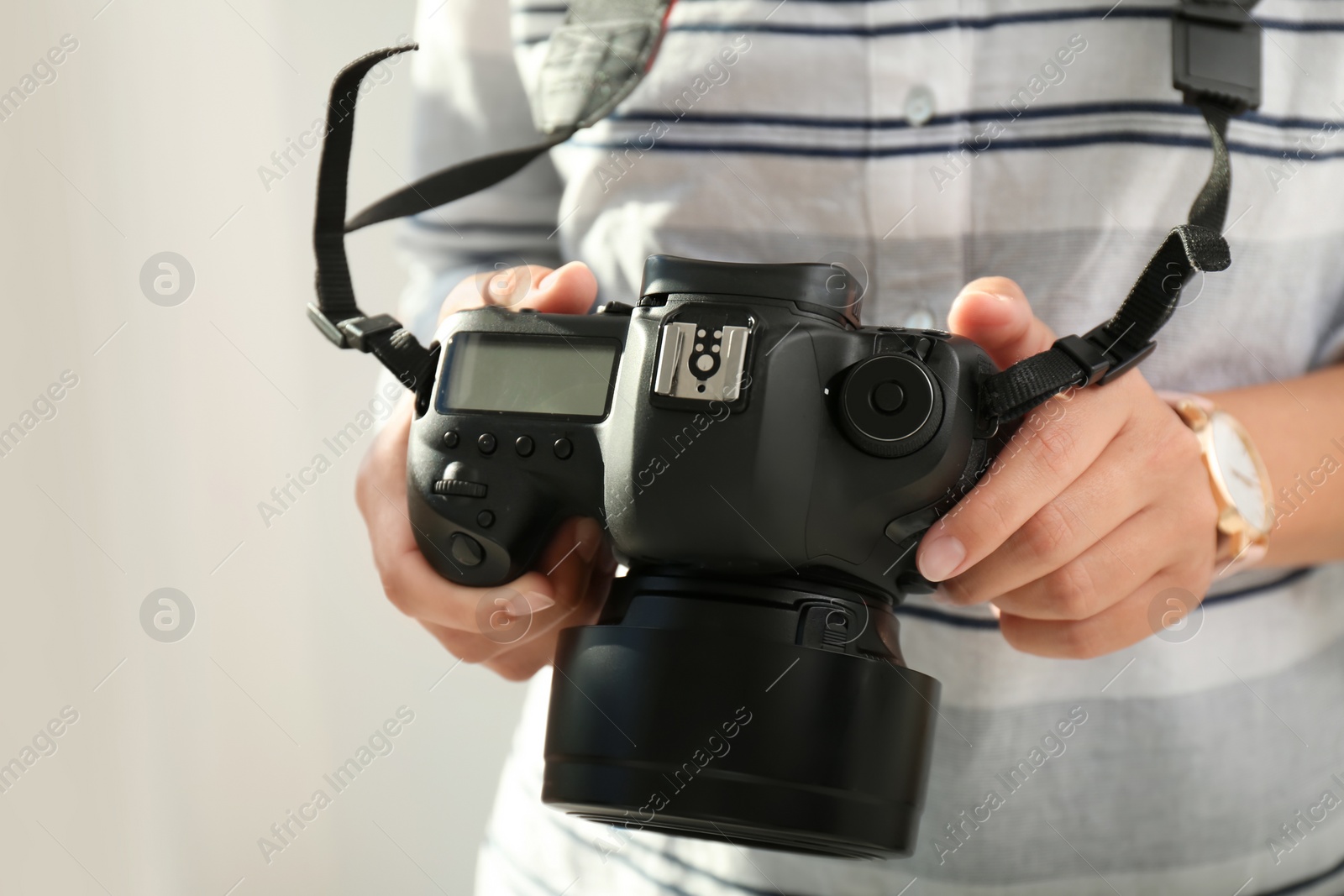 Photo of Female photographer with professional camera on blurred background, closeup