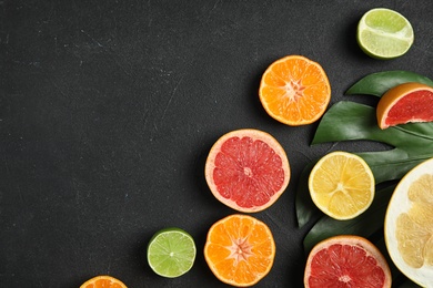 Photo of Different citrus fruits on black background, flat lay. Space for text