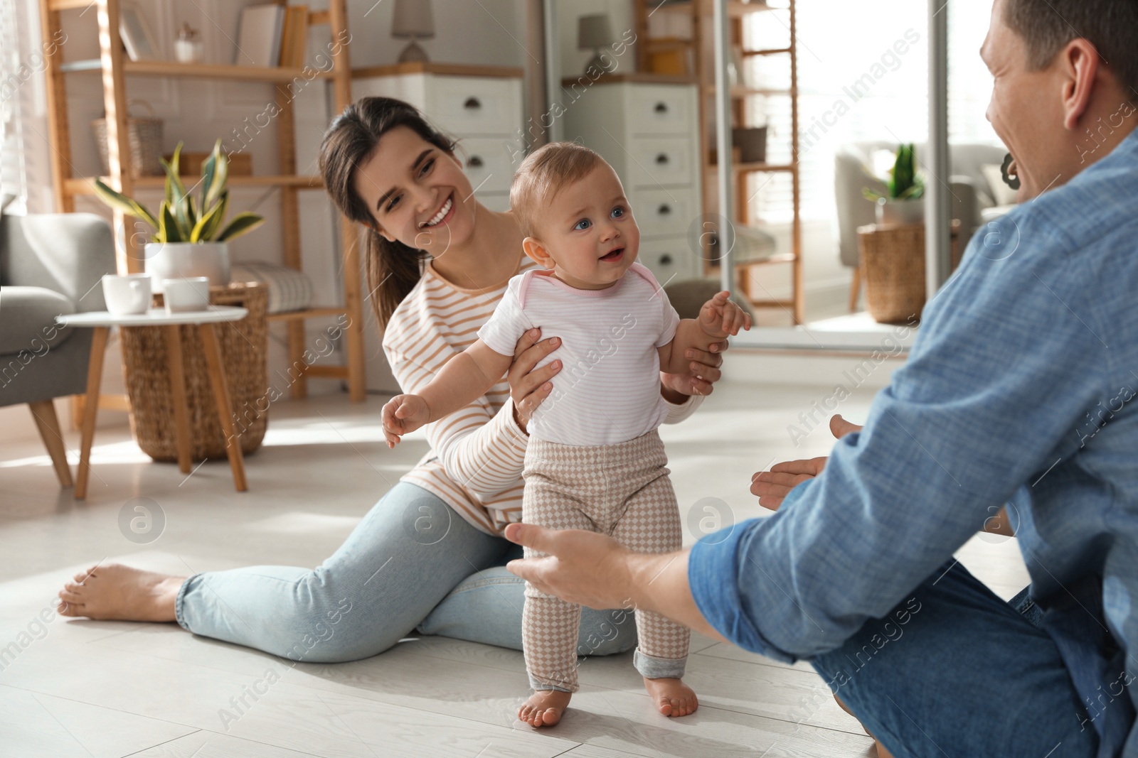 Photo of Parents supporting their baby daughter while she learning to walk at home