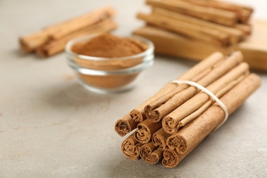 Photo of Aromatic cinnamon sticks on grey table, closeup. Space for text