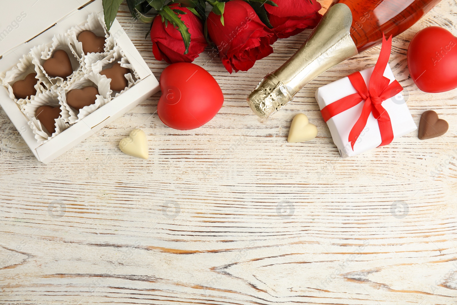 Photo of Flat lay composition with heart shaped chocolate candies on white wooden table, space for text. Valentine's day celebration