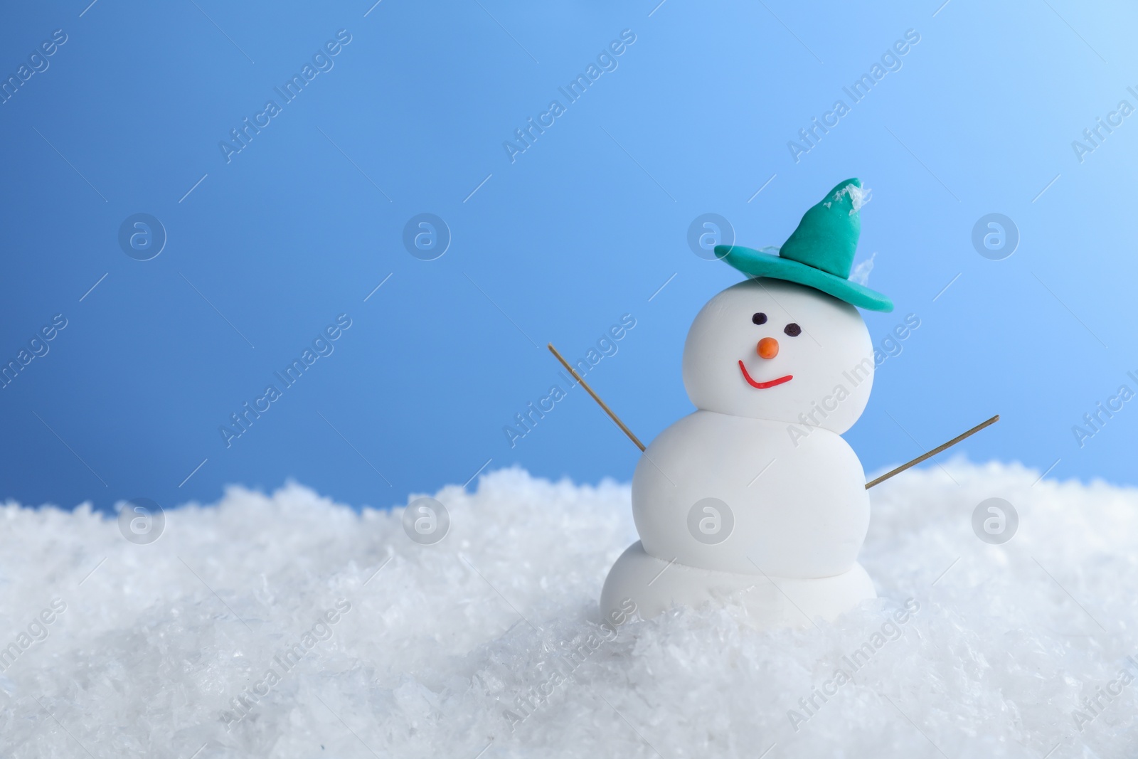 Photo of Funny snowman on snow against light blue background, space for text