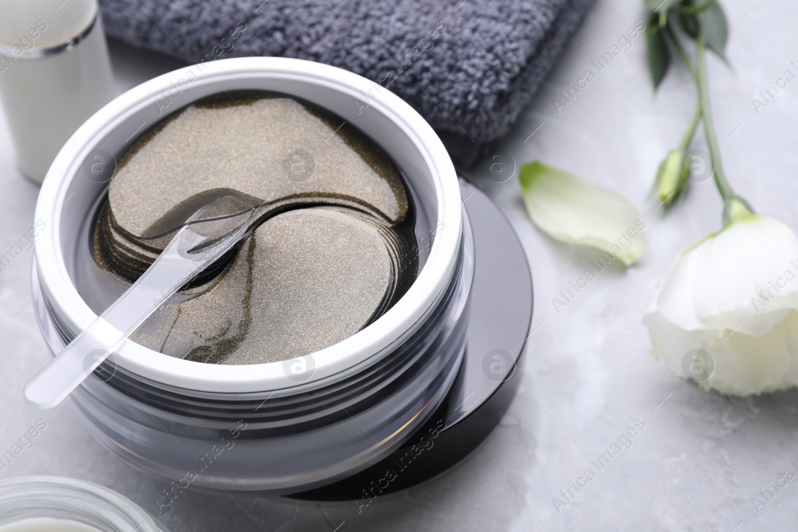 Photo of Package of under eye patches and flower on white marble table, closeup. Cosmetic product