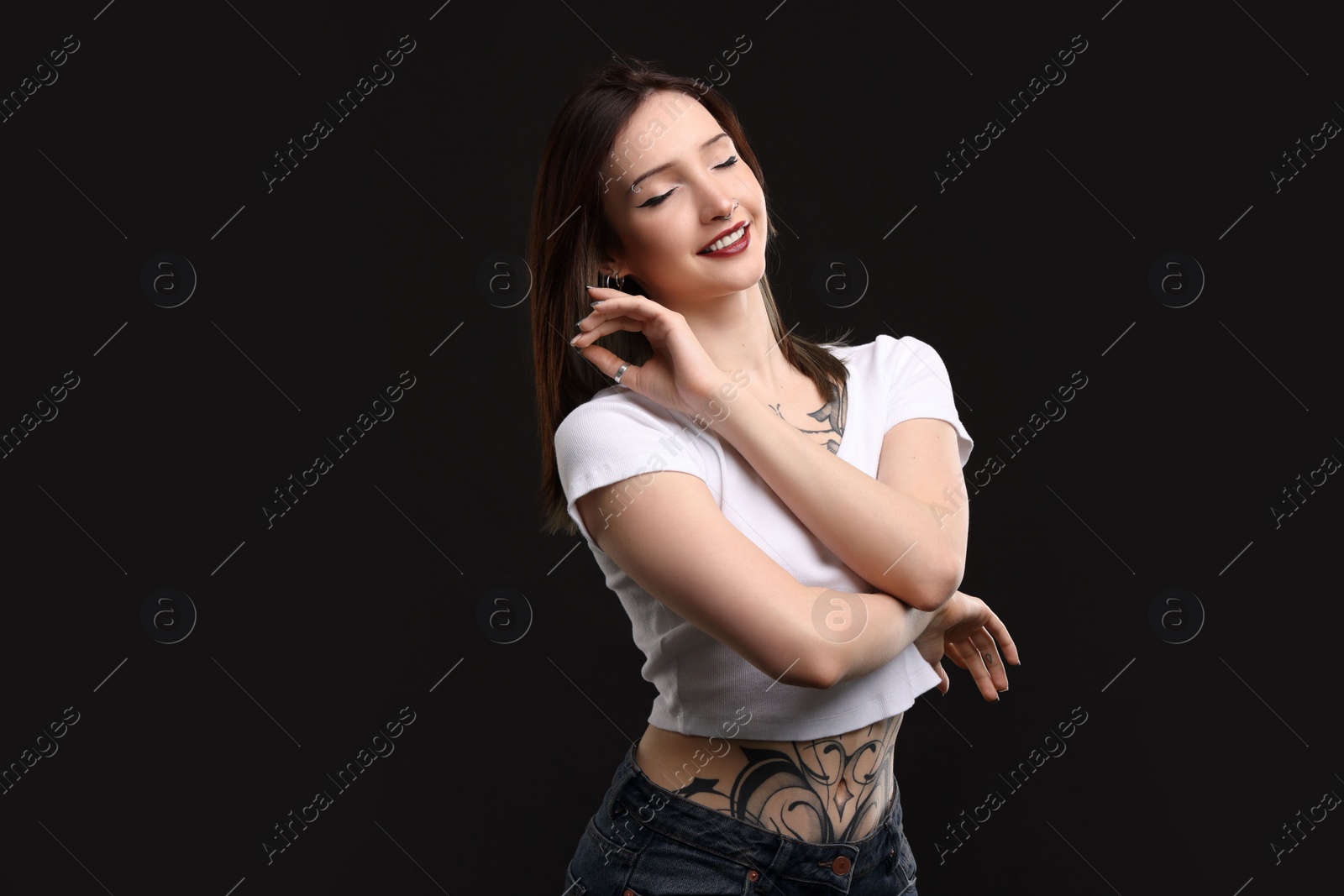 Photo of Portrait of smiling tattooed woman on black background. Space for text