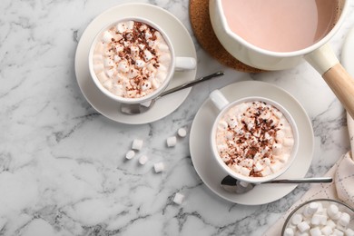 Aromatic hot chocolate with marshmallows and cocoa powder served on white marble table, flat lay. Space for text