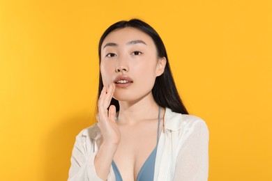 Photo of Beautiful young woman with makeup on orange background