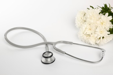 Photo of Stethoscope and chrysanthemum flowers on white background. Happy Doctor's Day