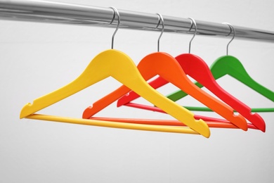 Photo of Clothes hangers on metal rail against light background