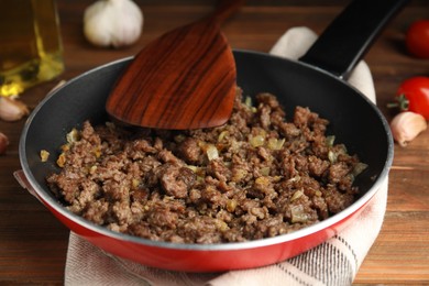 Fried minced meat with onion on wooden table, closeup