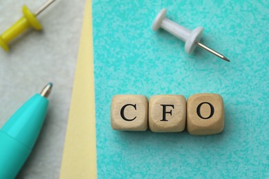 Abbreviation CFO of wooden cubes with stationery on color background, flat lay. Financial management