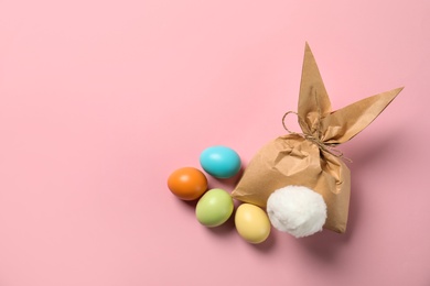 Photo of Flat lay composition of Easter bunny gift bag and dyed eggs on color background. Space for text