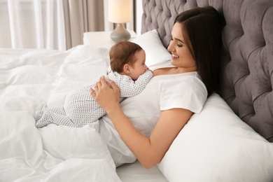 Happy woman with her cute baby on bed