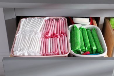 Photo of Open cabinet drawer with menstrual pads, tampons and pantyliners, closeup