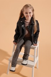 Photo of Fashion concept. Stylish girl posing on pale orange background