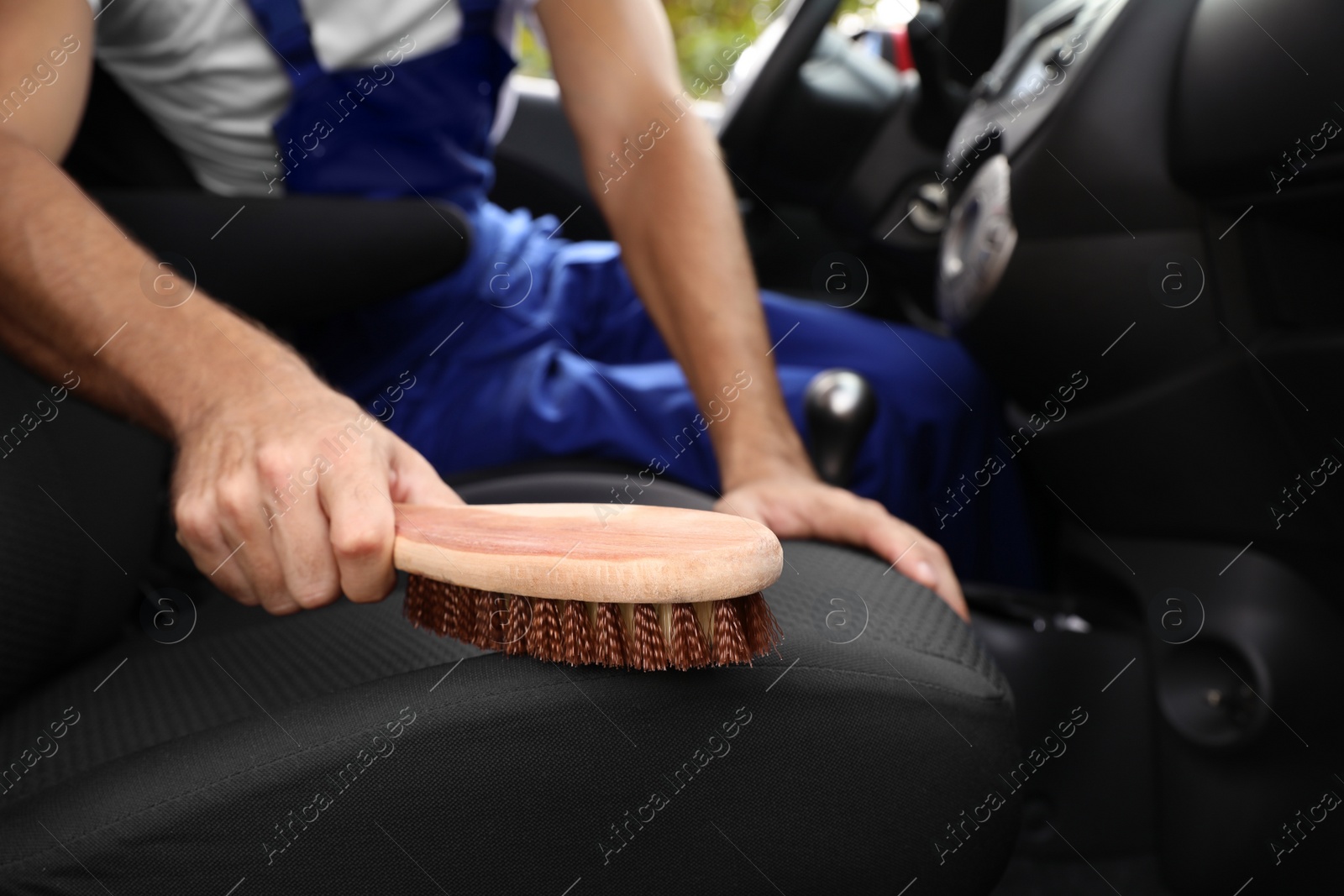 Photo of Man cleaning automobile salon with brush, closeup. Car wash service