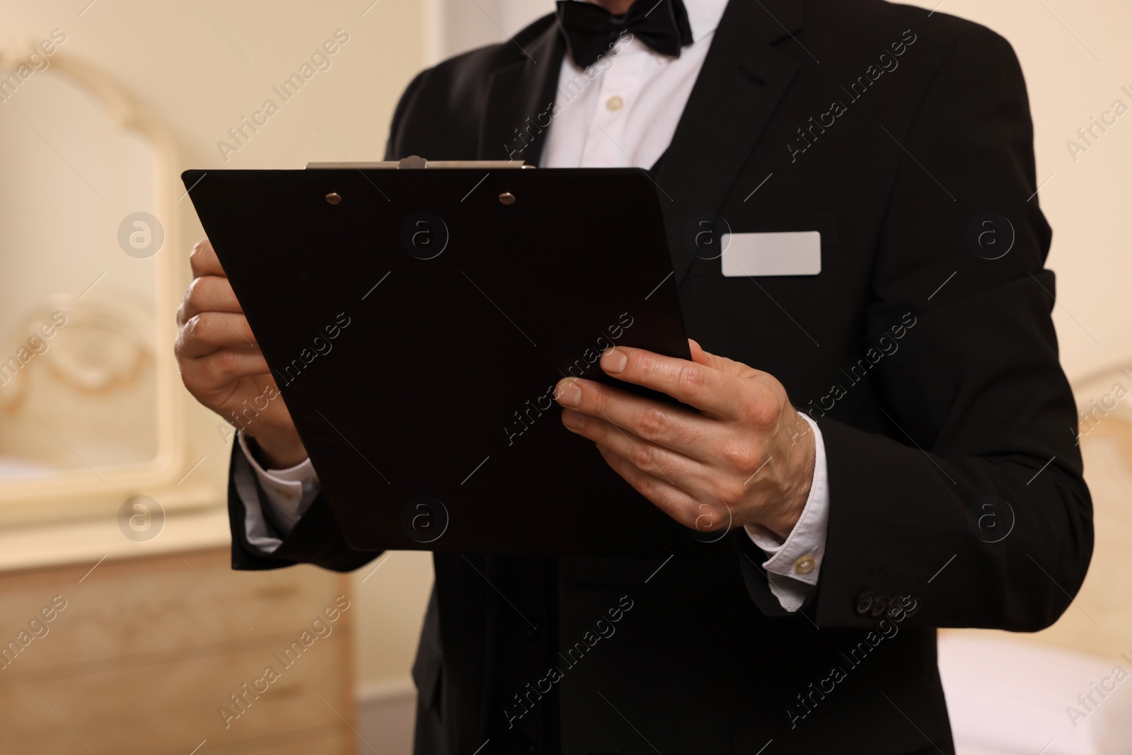 Photo of Man in suit with clipboard indoors, closeup. Professional butler courses