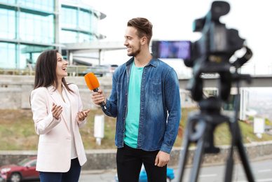 Young journalist interviewing businesswoman on city street