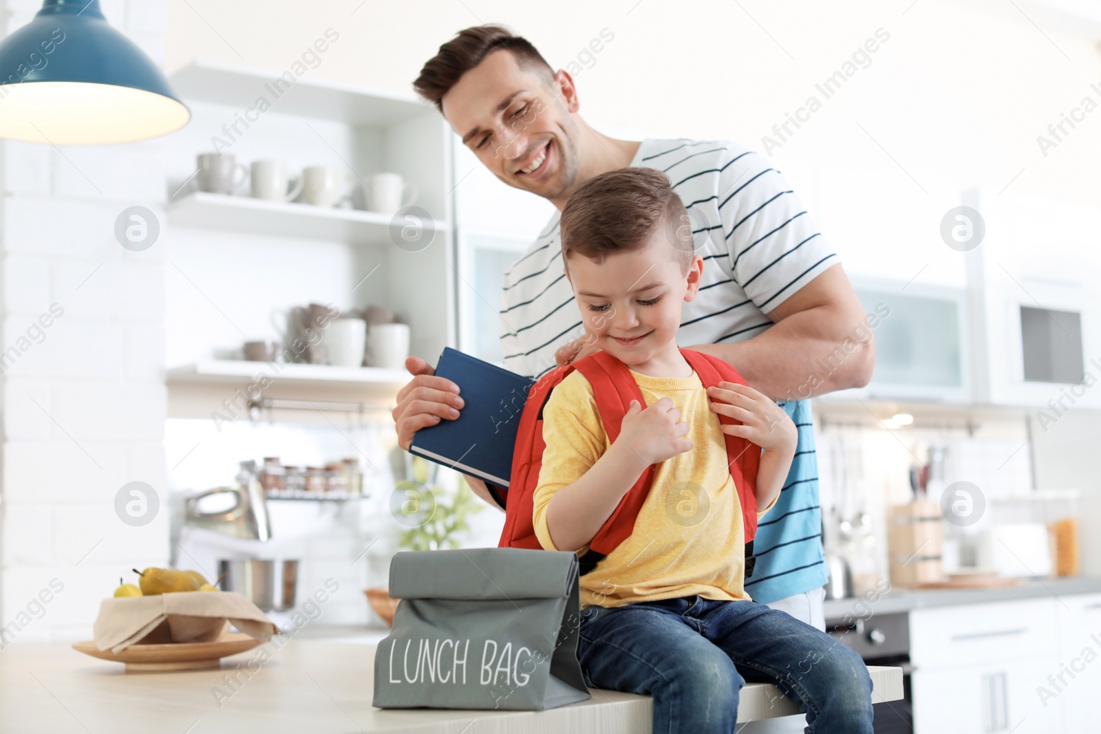 Photo of Young man helping his little child get ready for school at home