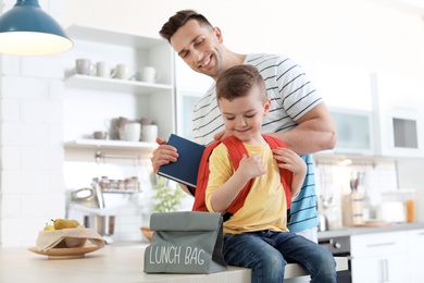 Young man helping his little child get ready for school at home