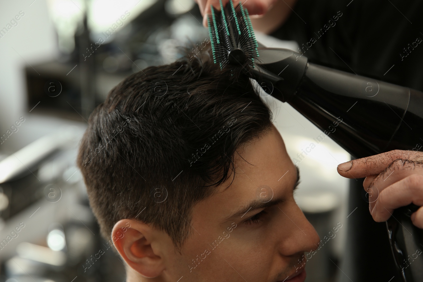 Photo of Professional barber making stylish haircut in salon, closeup