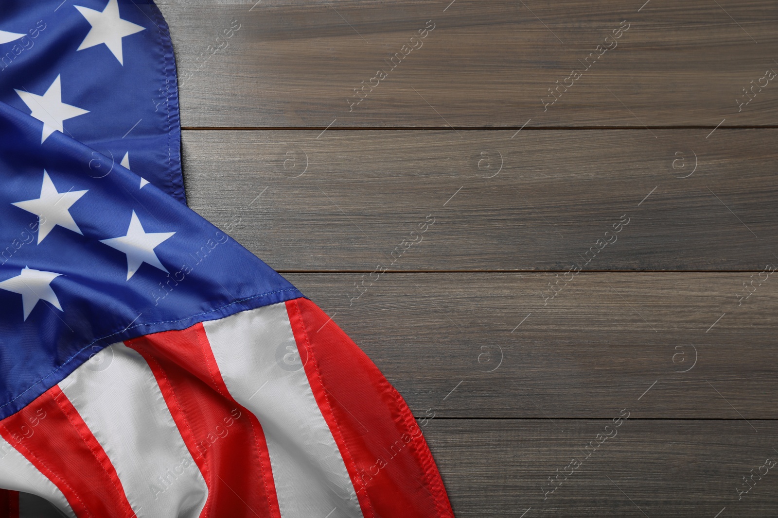 Photo of American flag on wooden table, top view. Space for text