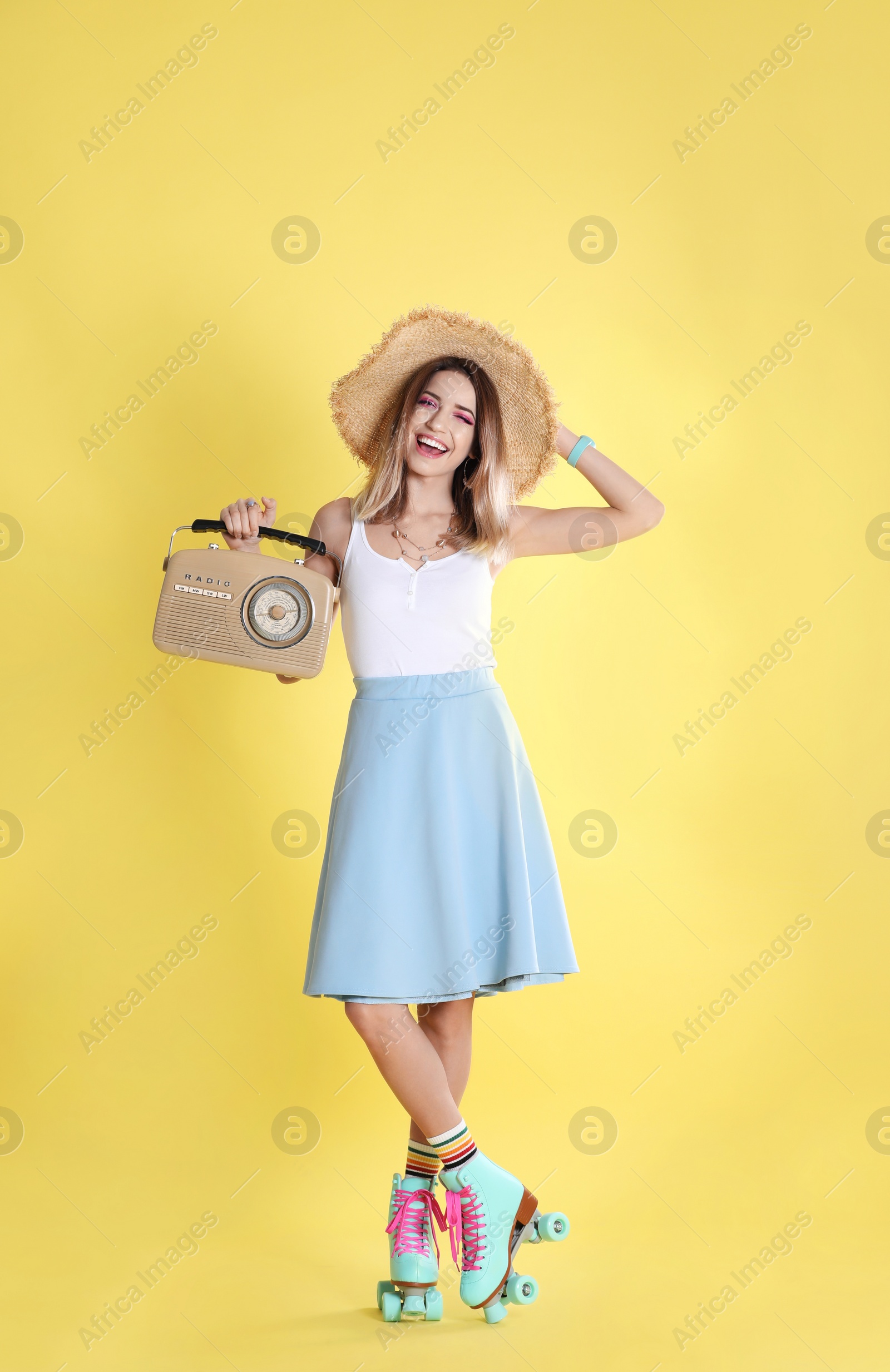 Photo of Young woman with roller skates and retro radio on color background