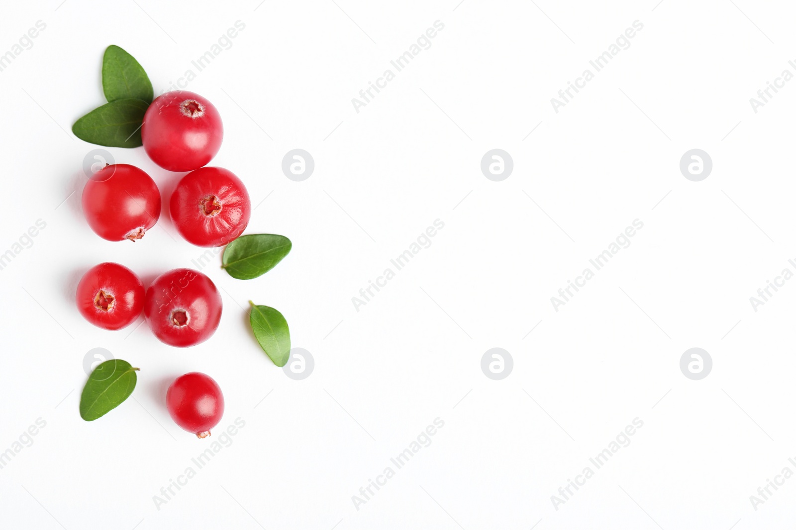 Photo of Fresh ripe cranberries and green leaves on white background, flat lay. Space for text