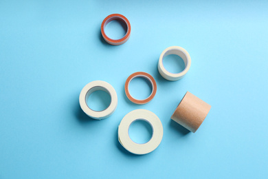 Photo of Sticking plaster rolls on light blue background, flat lay