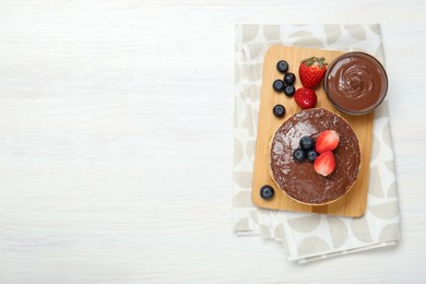 Photo of Tasty pancakes with chocolate paste and berries on white wooden table, top view. Space for text